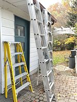 Group showing Featherlite step ladder and three aluminum extension ladders leaning against wall
