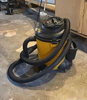 Side view of yellow/black Shop-Vac with hose and wheels