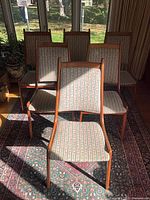 Front view of six teak dining chairs showing upholstery and frame