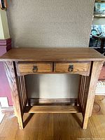 Front view of oak console table showing drawers, slatted sides, lower shelf