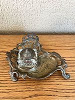 Top view of ornate cast metal inkwell showing glass insert and lid