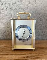 Full front view of Seiko desk clock showing brushed steel body, gold-tone trim and handle