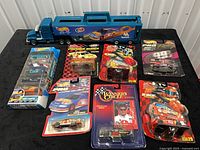Full lot overview with blue carrier truck, seven carded diecast packages, Wave Cravers 5-pack