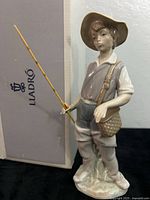 Front view of Lladro Boy Gone Fishing figurine beside box