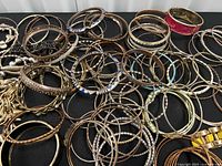 Top view showing majority of metal bangles, enamel pieces, chain bracelet and red faux-leather cuff