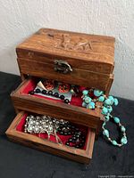 Overall view of carved wood jewelry box with drawers open showing assorted jewelry