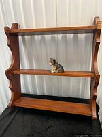 Front view of wooden wall shelf with figurine on middle tier