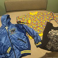 Three garments laid out: blue Mead jacket, Mars Attacks sweatshirt, multicolor sweatshirt