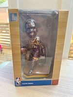 Front of boxed LeBron James bobblehead showing figure through clear window
