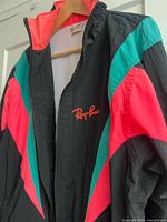 Front view of jacket on hanger displaying color panels and Ray-Ban logo