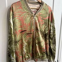 Front view of palm leaf bomber jacket showing print, zipper, pockets, striped ribbing