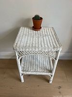 Front view of white wicker table showing top and shelf