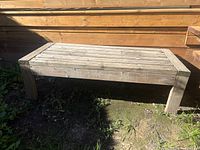 Full view of rectangular wooden bench against wall