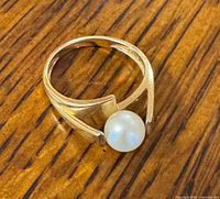 Angled view of gold ring showing open split shank and pearl