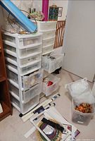 Overall lot showing two white plastic drawer towers filled with supplies, knitting looms, dowels, fiberfill