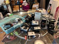 Overview of five Canon cameras, three lenses, two flashes, filters and accessories on table