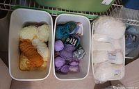 Three bins showing assorted yarn colours and packaged white skeins