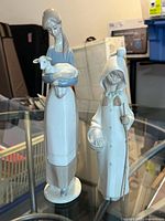 Front view of both Lladro figurines on glass table