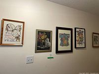 Five of the six framed needlework pieces hung on wall
