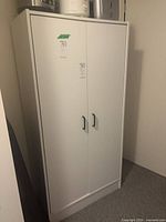 Front view of white two-door cupboard showing handles