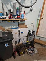 Overall lot showing shelf of chemicals, boxes, tool bag and storage bins