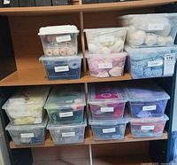 Shelving unit with multiple labelled clear bins of yarn