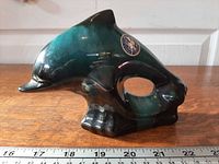 Full side view of dolphin figurine with ruler for scale