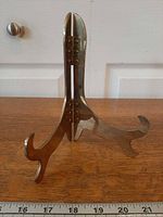 Front view of brass folding easel stand on tabletop with ruler for scale