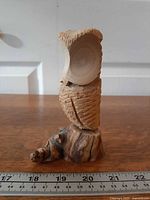 Front view of carved wooden owl on root base with ruler reference
