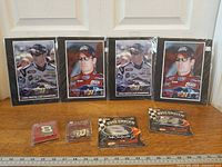 Four matted NASCAR photographs with three packaged emblems on table