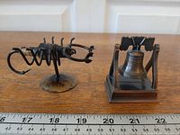 Liberty Bell sharpener and metal scorpion side-by-side with ruler for scale