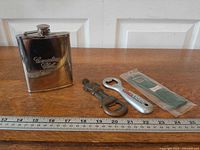Group shot of flask and three bottle openers with ruler for scale