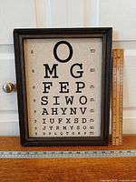 Full view of framed Snellen eye chart with ruler for scale