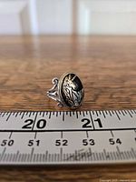 Front view of oval unicorn ring beside ruler for scale