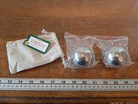 Full set showing two sealed stainless steel balls, cotton pouch, and ruler for scale