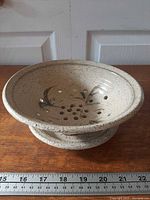 Top view of strainer on catch plate showing holes and design with ruler for size