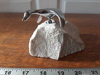 Side view of aluminum bird sculpture on stone base