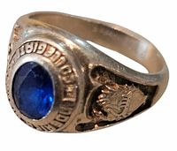 Three-quarter view displaying blue stone, surrounding text, and crest detail