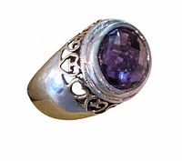 Three-quarter view showing bezel-set faceted purple stone and heart filigree shoulders