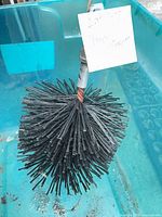 Black round chimney brush head with threaded adapter shown in blue bin