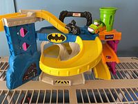 Full view of Batcave/Joker spiral ramp playset with two vehicles positioned on top