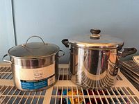 Two stainless steel stock pots on rack