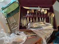 open chest showing assorted flatware, loose utensils, carving set and roll