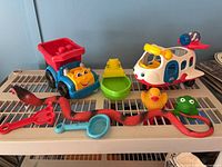 Overview of toddler toys on shelf showing helicopter, dump truck, boat, duck, frog, snake, shovel, scoop
