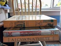 Spine view of Norman Rockwell book atop two other volumes, shows thickness and edge wear