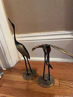 Front view of both brass crane heron figurines