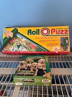 Roll-O-Puzz storage mat box and panoramic puzzle box on shelf