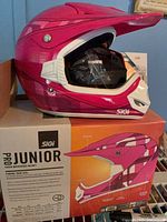 Left side view of pink SiGi Pro Junior helmet on original box