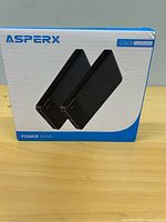 Front of sealed AsperX box showing two black power banks
