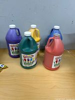 Five large Colorations paint bottles on table showing colors